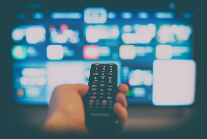 Neuerungen November 2025: Hand mit Fernbedienung vor einem HD-Fernseher.